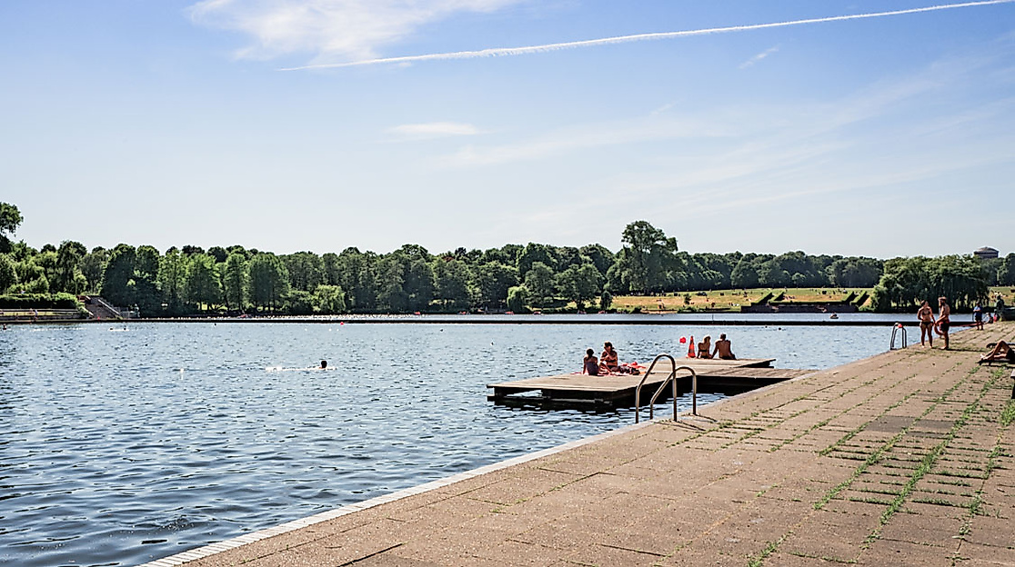 Badegäste auf Holzstegen und am Sandstrand des Naturbad Stadtparksees in Hamburg bei sonnigem Wetter