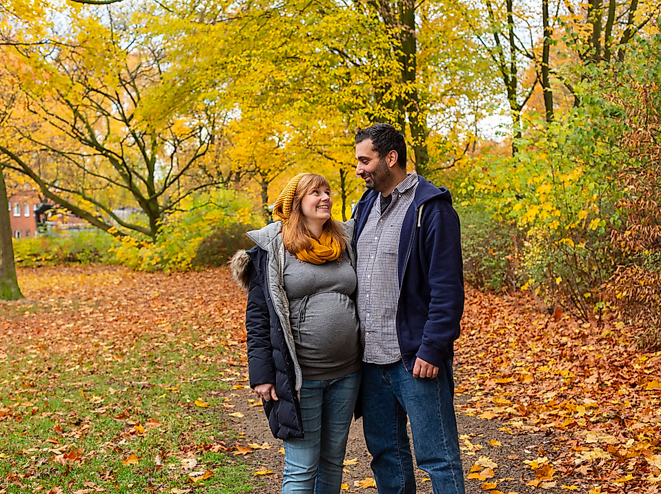 Paar im herbstlich bunten Park, eng umschlungen und lächelnd beim Spaziergang durch Laub in Hamburg