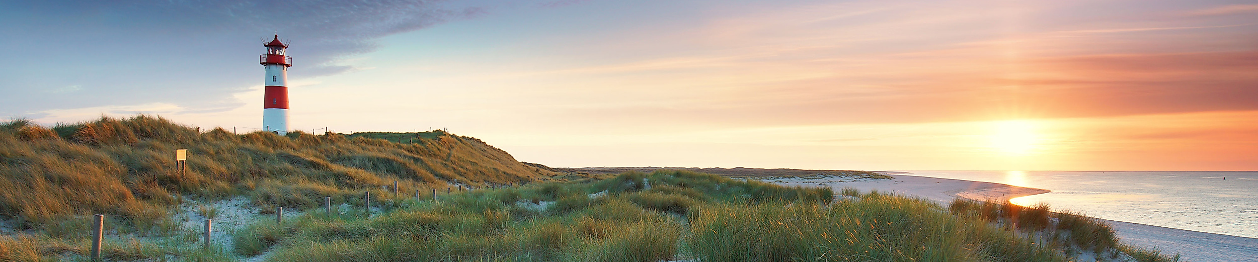 Panoramablick auf Sylt mit Leuchtturm in den Dünen und Sonnenuntergang über der Nordsee