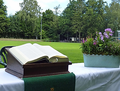 Aufgebauter Altar mit Bibel und Blumenschmuck auf einem Fußballfeld