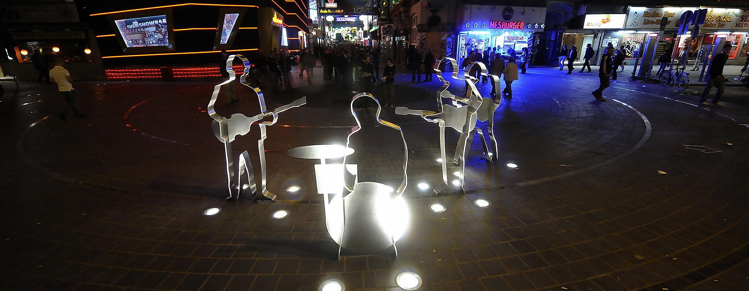 Beleuchtetes Beatles-Platz-Denkmal auf der Reeperbahn bei Nacht mit umliegenden Clubs