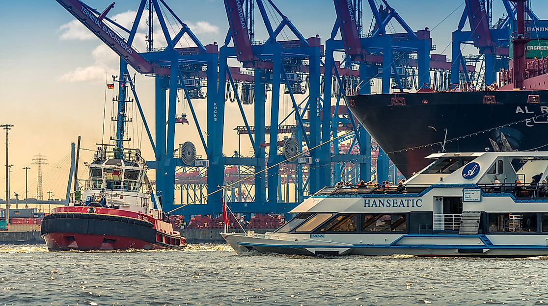 Schiffe vor Containerkränen im Hamburger Hafen bei Sonnenuntergang, mit Hafenschlepper, Ausflugsdampfer und Containerschiff auf der Elbe