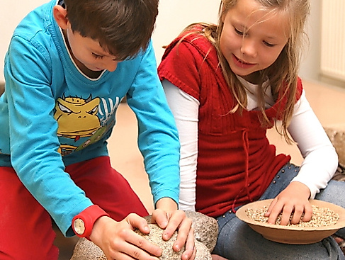 Kinder beim Kornmahlen