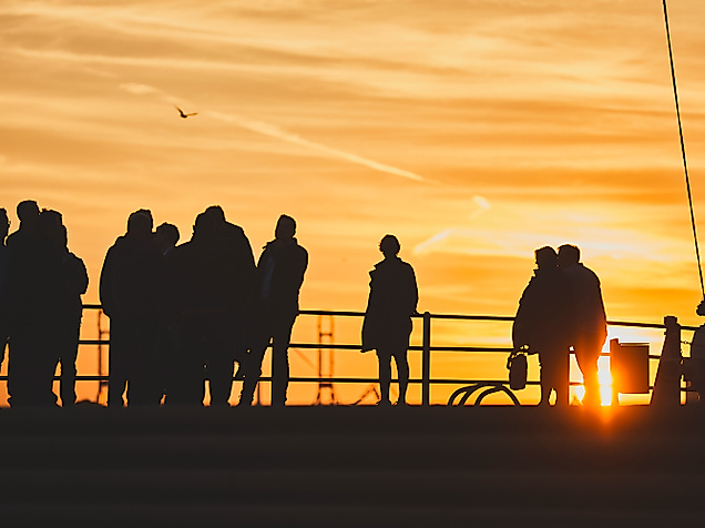 Silhouetten von Menschen  beim Sonnenuntergang an der Hamburger Hafenkante.