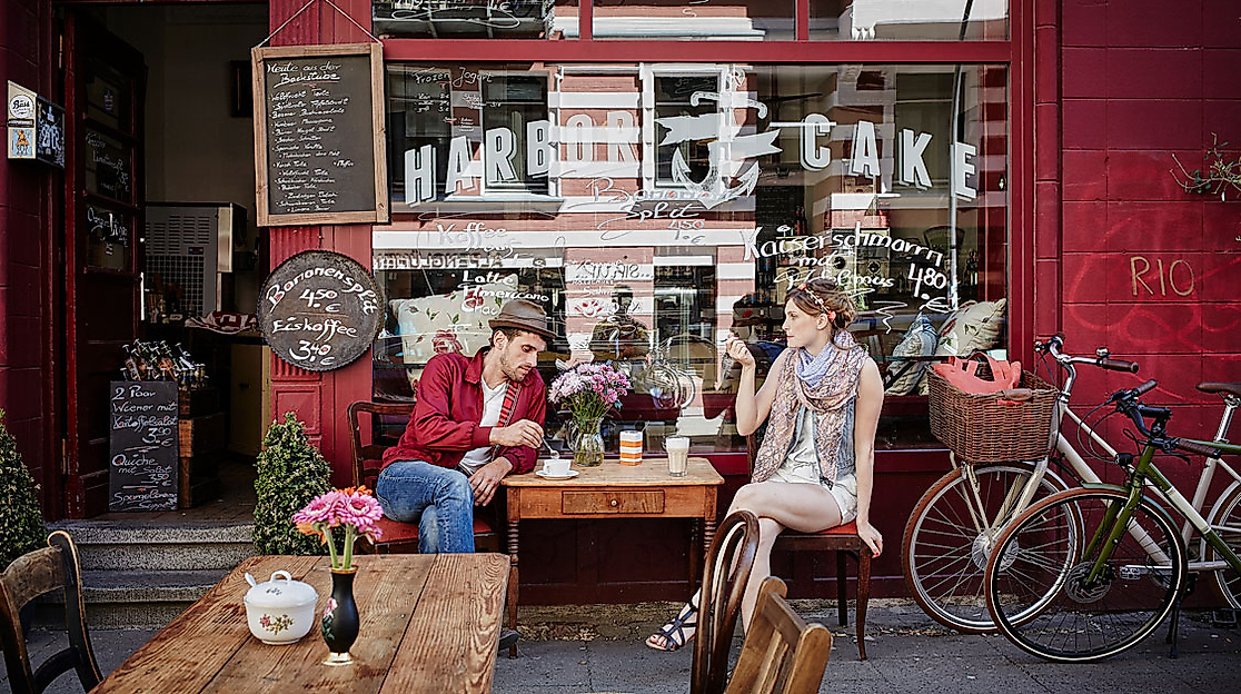 Zwei Personen sitzen vor einem gemütlichen Café im Karoviertel und genießen Getränke.