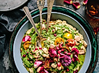 Farbenfrohe vegetarische Bowl mit Gemüse, Kräutern und essbaren Blüten, stilvoll angerichtet mit Besteck