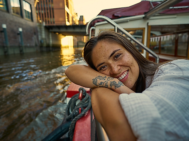 Eine junge Frau lehnt sich auf dem Deck eines Bootes an.