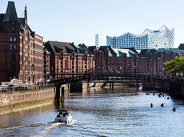 Blick auf Hamburger Speicherstadt mit Boot im Kanal und Elbphilharmonie im Hintergrund bei Sonnenschein