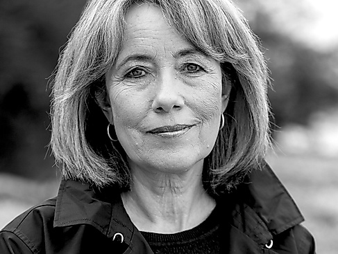 Schwarz-Weiß-Porträtfoto einer Frau mittleren Alters mit Bob-Frisur. Sie trägt Kreolen und eine dunkle Jacke.