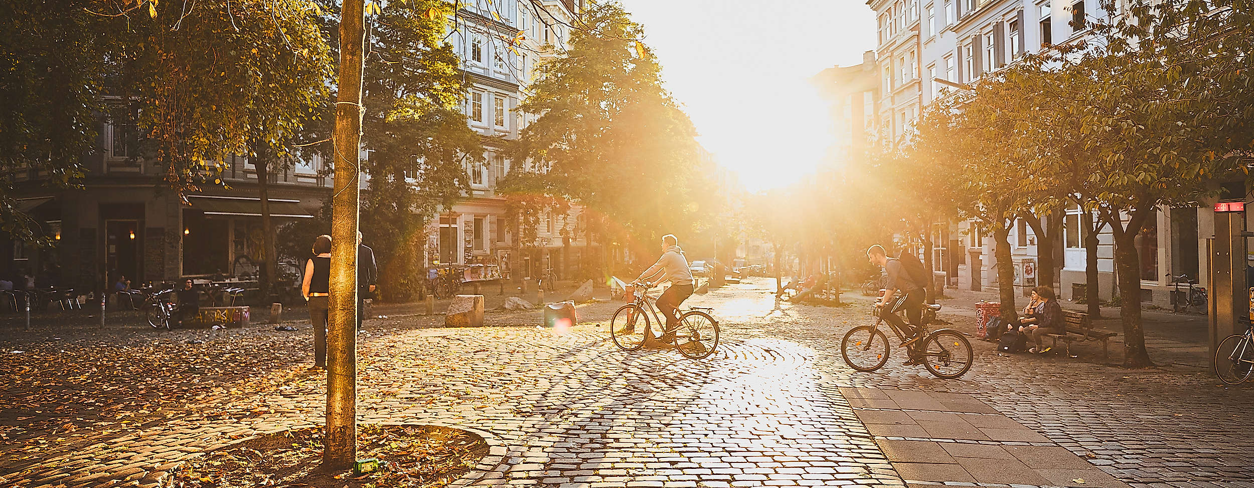 Hein-Köllisch-Platz in Hamburg Ottensen im Gegenlicht der Abendsonne mit Bäumen und Straßencafés