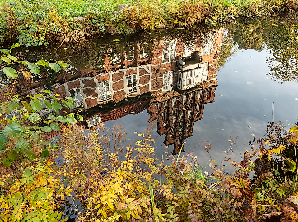 Spiegelung des Bergedorfer Schlosses im Wassergraben, umrahmt von herbstlicher Vegetation in Hamburg-Bergedorf