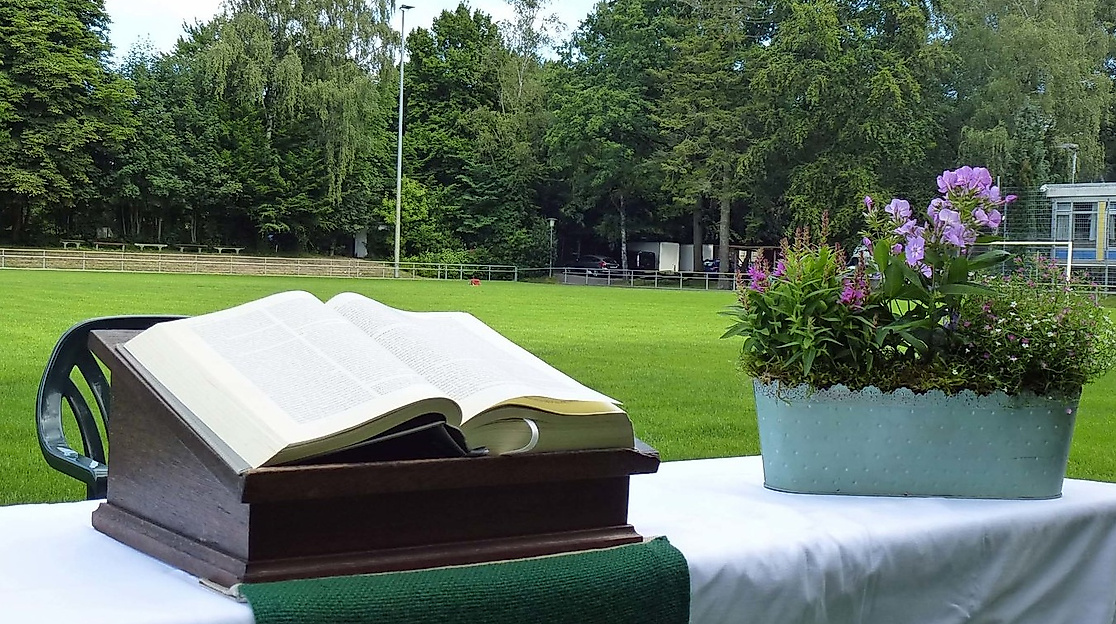 Aufgebauter Altar mit Bibel und Blumenschmuck auf einem Fußballfeld