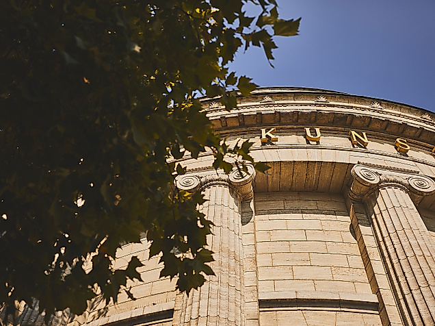 Nahaufnahme der hellen Rundfassade der Hamburgischen Kunsthalle mit Blattwerk im Vordergrund.