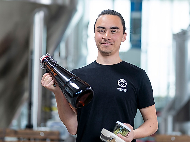 Junger Mann mit Bierflasche und Brauzutaten in Brauerei bei der Hamburg Beer Week