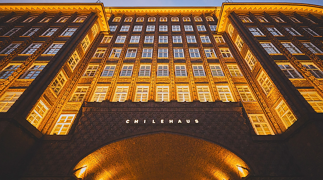 Beleuchtete Fensterfront und Torbogen des Chilehauses in Hamburg bei einsetzender Dämmerung
