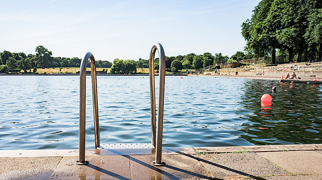 Einstiegstreppe ins Wasser des Naturbad Stadtparksees in Hamburg mit Blick auf Badegäste und Sandstrand bei Sonne