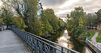 Fußgängerbrücke über dem Isebekkanal in Hamburg-Eimsbüttel mit Bäumen und Spazierweg bei Abendlich