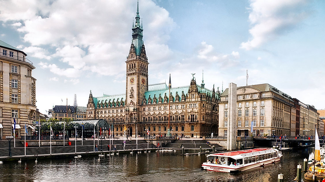 Blick vom Alsterfleet auf das Hamburger Rathaus mit Ausflugsschiffen, Arkaden und belebter Promenade