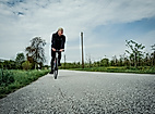 Radfahrer auf einem Feldweg in Finkenwerder, umgeben von Obstbäumen und weitem Himmel