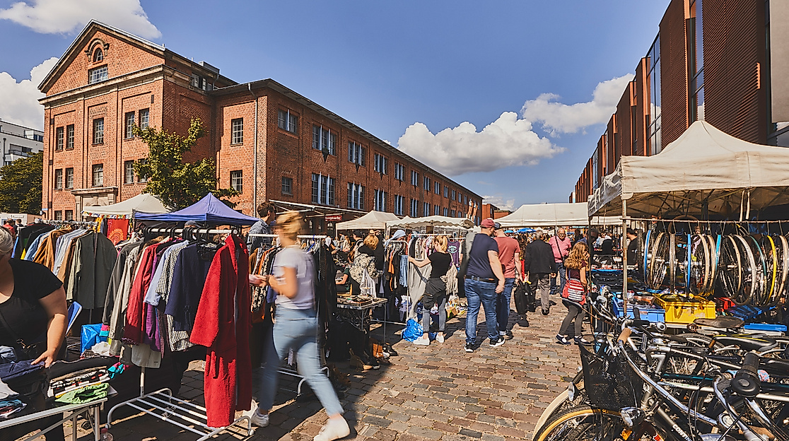 Menschen schlendern bei Sonnenschein über den Flohmarkt Flohschanze zwischen Backsteingebäuden in Hamburg