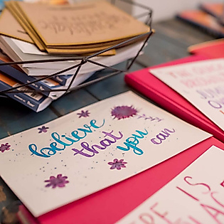 Kreativ gestaltete Lettering-Karten mit bunten Schriftzügen und Illustrationen auf Tisch mit Workshop-Materialien