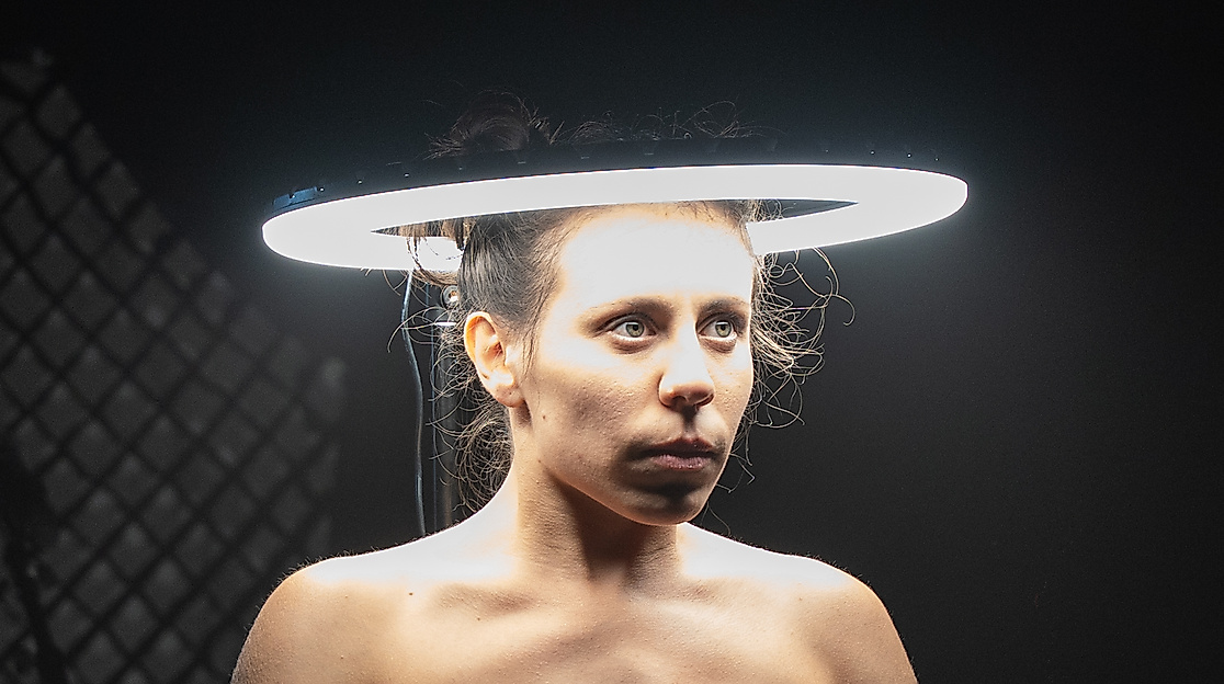 Der Kopf einer Performerin ist von einem runden, hellen Lichtkreis umgeben.
