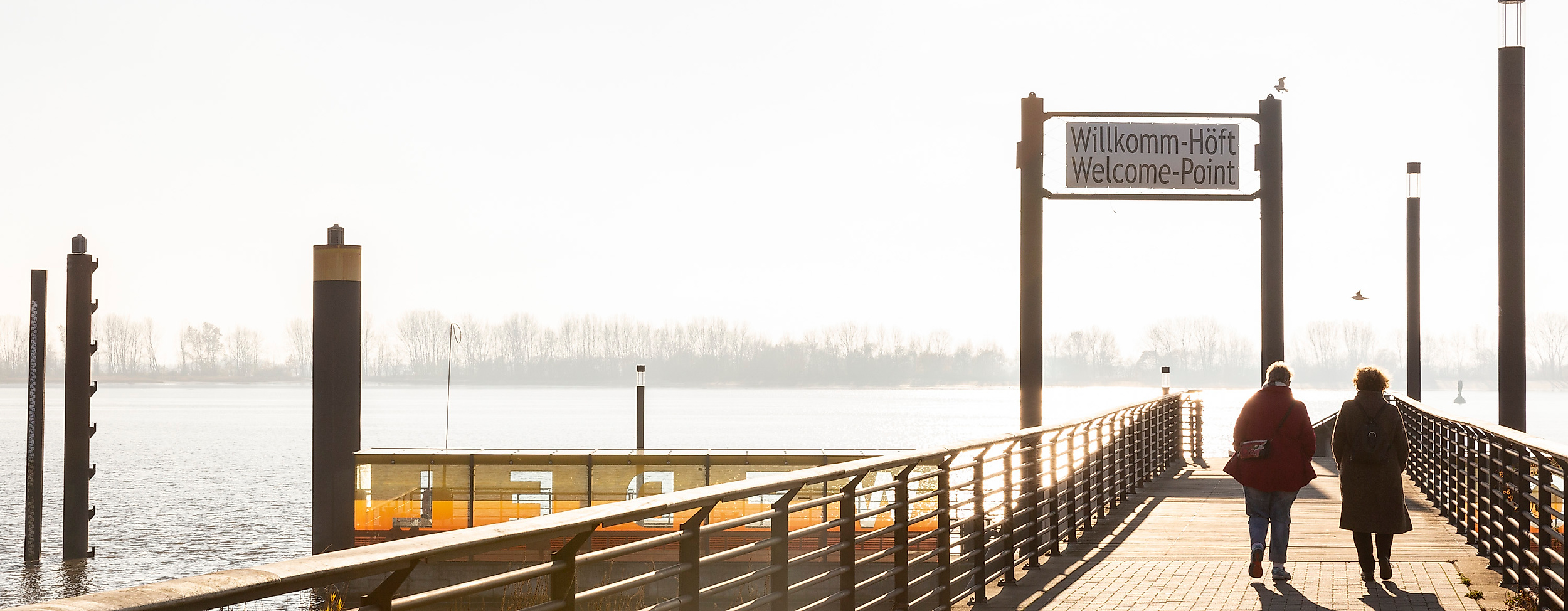 Spaziergänger:innen auf dem Anleger Willkomm Höft in Hamburg mit Blick auf die Elbe