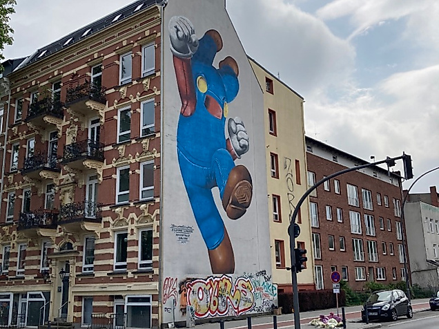 Großes Wandbild an Hamburger Hausfassade zeigt blaue Cartoonfigur mit Herz in der Hand, Teil der Millerntor Gallery