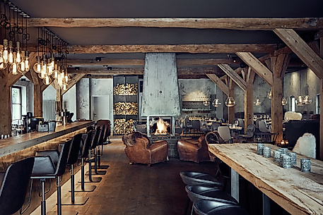 Gemütliches Interieur der HYGGE Brasserie & Bar in Hamburg mit Kamin, Holzdecken und nordischem Design