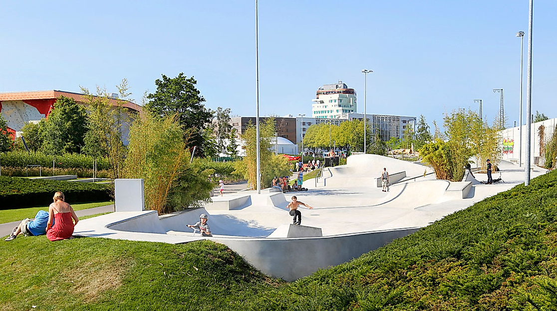 Skateanlage im Inselpark Wilhelmsburg bei Sonnenschein, umgeben von Grünflächen und modernen Gebäuden