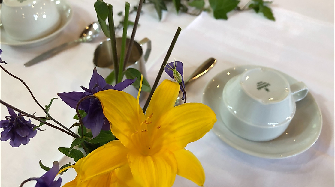 Ausschnitt Kaffeetafel: Umgedrehte Kaffeetassen und Blumenschmuck (Akelei und Taglilie)