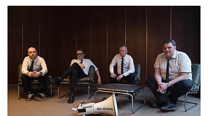 Die vier Mitglieder von Boy Division tragen alle ein weißes Hemd und eine schmale, schwarze Krawatte; sie sitzen lässig in einem Konferenzzimmer im Stil der 60er, vor ihnen liegt ein weißes Megafon, beschriftet mit dem Namen der Band.