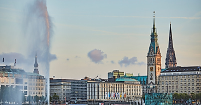 Blick über die Binnenalster auf das Hamburger Rathaus und die Alsterfontäne bei Abendlicht