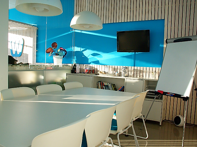 Modern gestalteter Coworking-Space in Hamburg mit großem Tisch, Flipchart und TV in kreativem Ambiente.