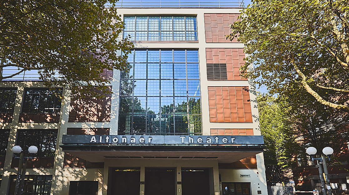Fassade des Altonaer Theaters mit moderner Glasfront, umgeben von Bäumen bei Tageslicht