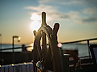 Historisches Schiffssteuerrad im Sonnenlicht auf einem Deck mit Blick auf das Wasser