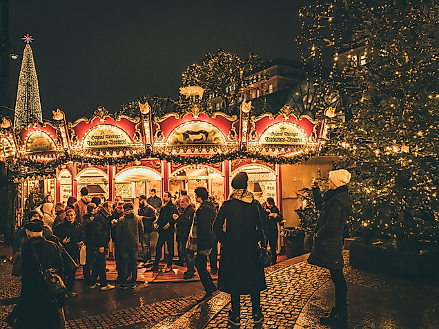 Illuminated carousel and festively decorated Christmas tree at the Christmas market at night