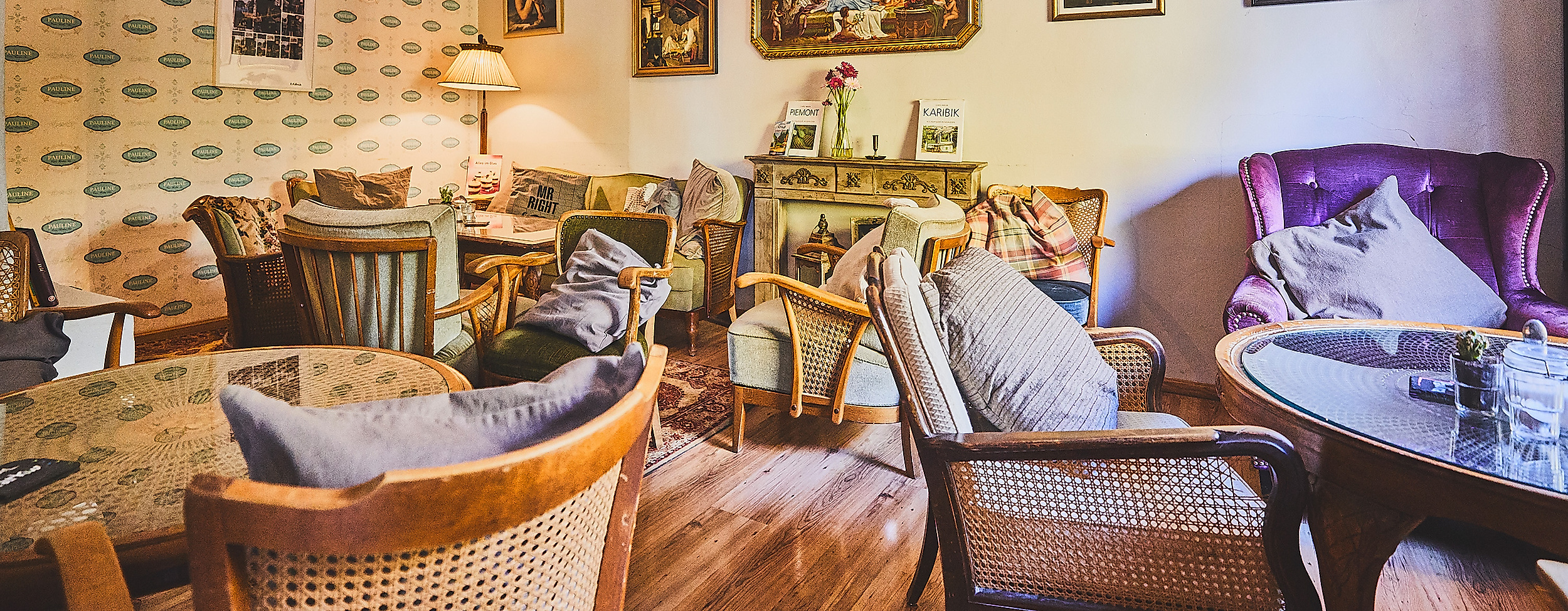 Verspielter Innenraum des Cafes Pauline mit Vintage-Möbeln, Blumen und Wandbildern.