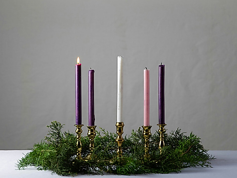 eine Kerze brennt in einem Gesteck