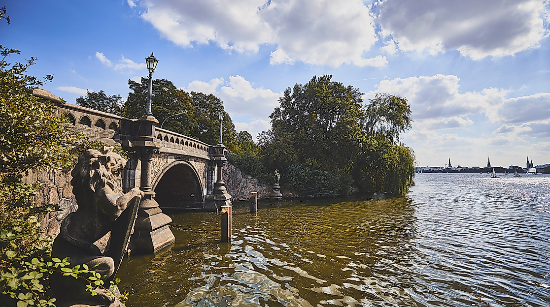 Steinerner Brückenbogen der Feenteichbrücke mit Blick über den Feenteich und die Skyline Hamburgs