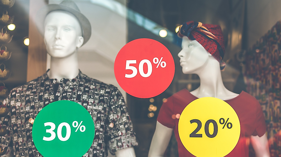 Schaufenster mit Rabattaufklebern in Rot, Gelb und Grün mit 20 %, 30 % und 50 % Sale-Aktionen