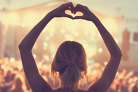 Frau formt mit Händen ein Herz vor beleuchteter Bühne beim Kultursommer