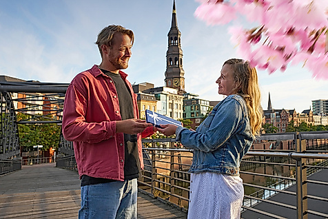 Ein Mann überreicht einer Frau einen Hamburg Gutschein