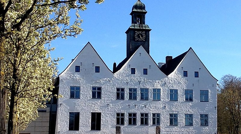 Weißes Herrenhaus vor blauem Himmel im Sonnenschein.