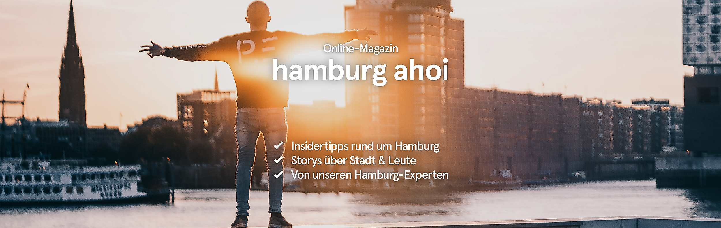 Die Sonne strahlt während ein Mann vor der Hamburger Kulisse die Arme ausbreitet