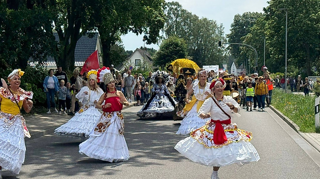 Tänzerinnen in weiß-bunter Gewandung führen den Festumzug an