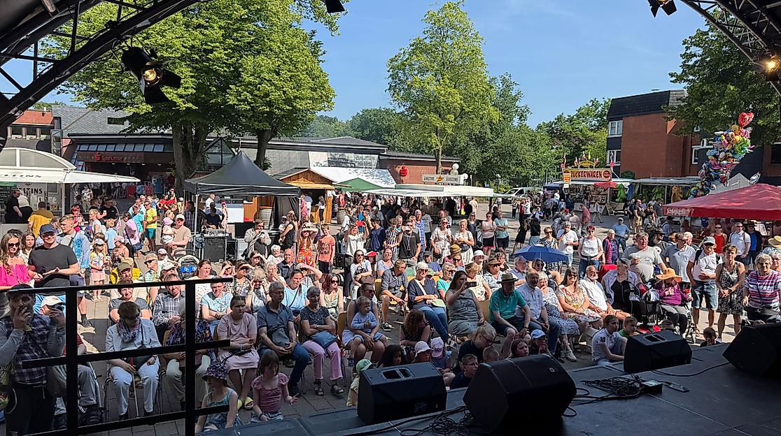 Blick von der Bühne auf den mit Zuschauern gefüllten Marktplatz im Sonnenschein