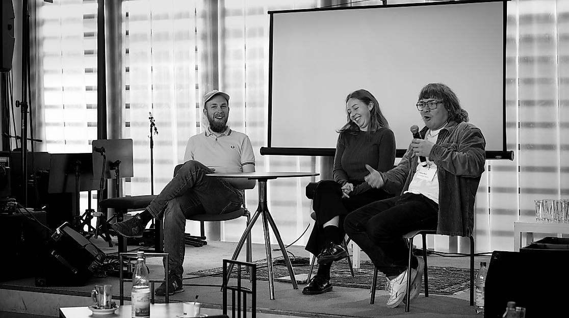 Drei Personen sitzen auf einem Panel und unterhalten sich.