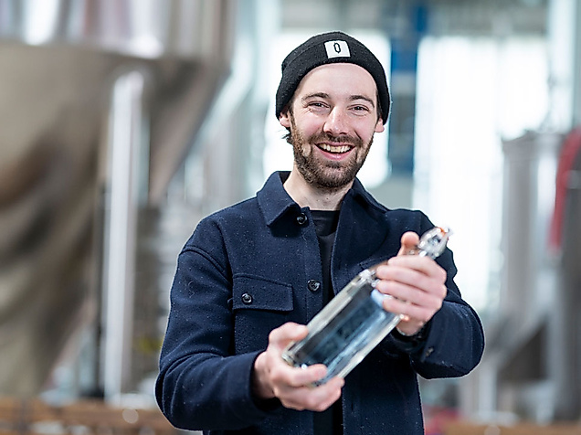 Brauer mit schwarzer Mütze hält Bierflasche in Brauerei während der Hamburg Beer Week