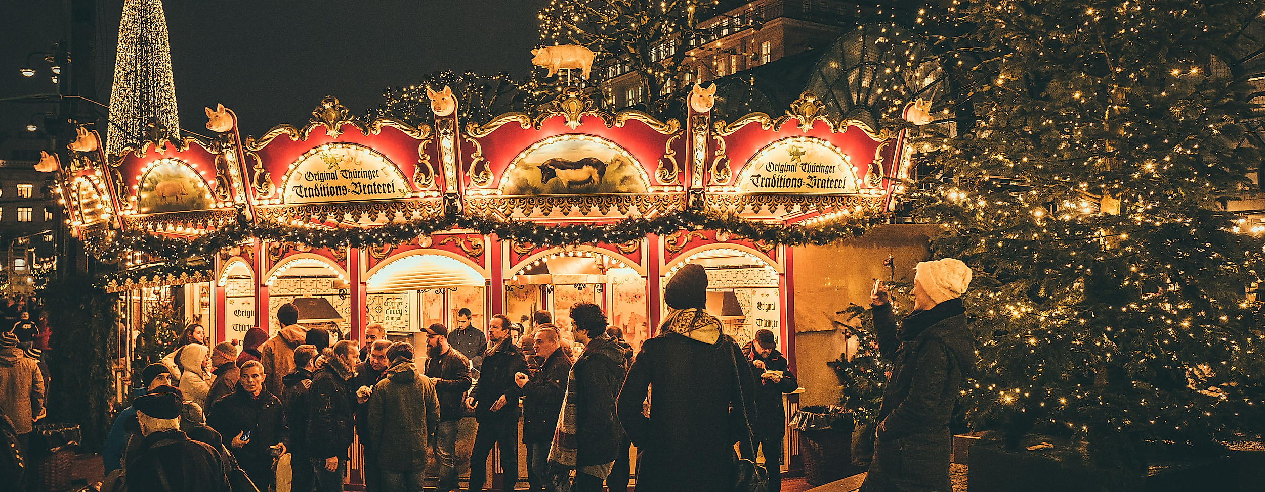 Illuminated carousel and festively decorated Christmas tree at the Christmas market at night